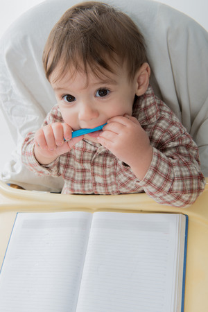 Little baby boy is playing with pen and note bookの写真素材