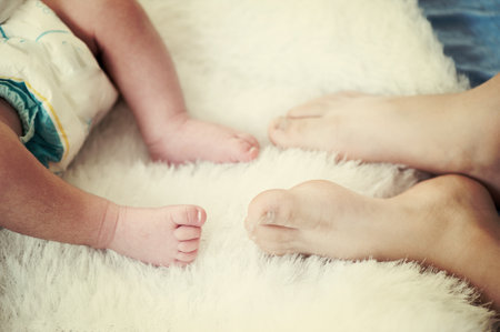 Feet of a newborn baby . Happy Family ,Mum and Dad hug their babys legs.High quality photo