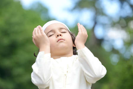 A little Arabic boy praying outdoor in natureの写真素材