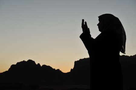silhouette of a muslim woman praying on the desertの写真素材