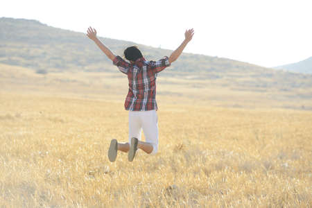 Young man jumping on yellow meadowの写真素材