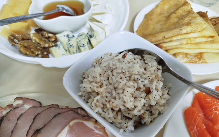 Delicious spread of dishes with rice, cured meat, assorted cheeses, and pancakesの写真素材