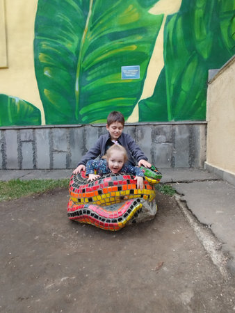 Children play on mosaic lizard sculptureの写真素材