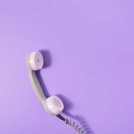 Retro style visual with phone receiver on pastel purple background. Minimal flat lay. Communication scene with copy space.の写真素材