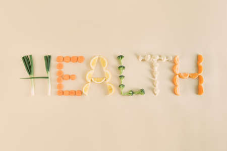 Healt word written out of fruit and vegetable slices. Health and vegan concept. Raw food idea. Minimal flat lay visual. Nature and organic aesthetic.の写真素材