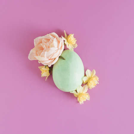 Minimal spring arrangement with green Easter egg and flowers on purple background. Flat lay composition. Spring aesthetic.の写真素材