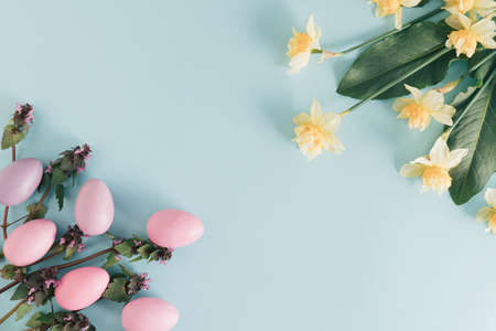 Spring and Easter concept with flowers and Easter eggs on bright blue background. Minimal flat lay...