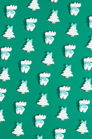 Creative composition made of gingerbread christmastrees and reindeers against green background....