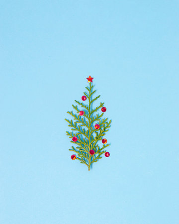 Minimal Christmas three concept  made of a single branch and sparkling confetti. Blue background flat lay scene.の写真素材