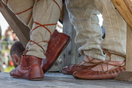 Old Russian leather sandals on mens feet on the wooden floorの写真素材