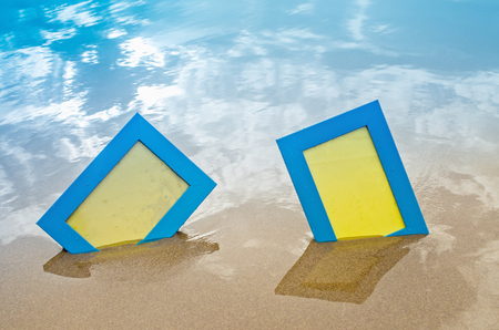 Blank photo frames on the beach with sky reflection on the wet sand . Summer vacation conceptの写真素材