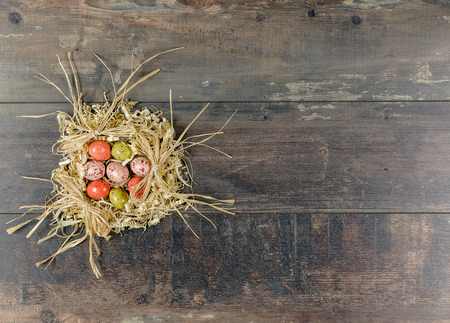 Chocolate colored eggs in the nest of sawdust on a background of brown wood.の写真素材
