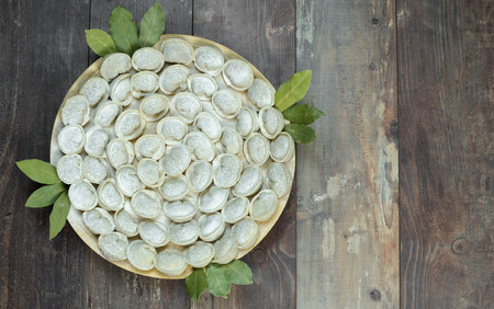 Meat dumplings - russian pelmeni on a round plate and wooden background. Top viewの写真素材