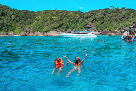 Cheerful young people in masks engaged snorkeling near the tropical islands.の写真素材