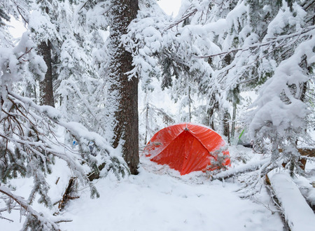 Red tent in winter forest. Tourist camp in snowy forest. Tent in the snow in winterの写真素材