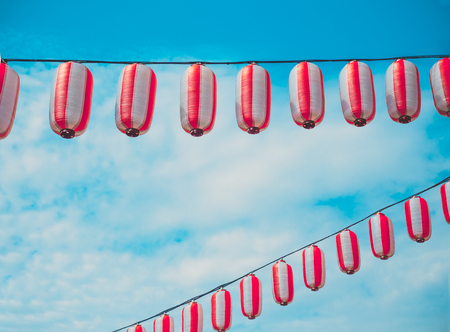 Paper red-white japanese lanterns Chochin hanging on blue sky background. Summer backgroundの写真素材