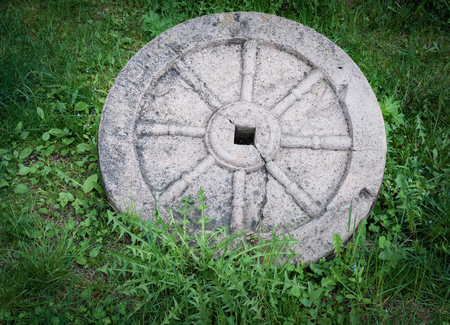 Stone granite wheel with rusted metal rim isolated on whiteの写真素材