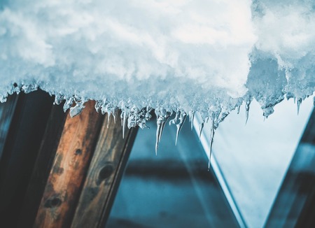 ice icicles hanging from roof of house.の写真素材