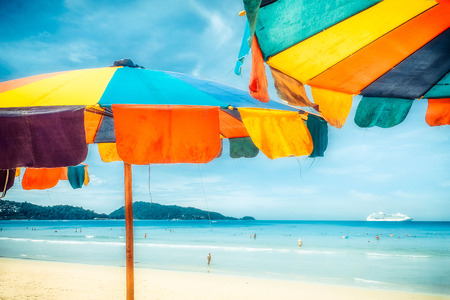Two colorful sunshades in the beach on a sunny summer day. Summer background with colorful beach umbrellas.