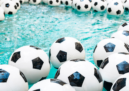 Many black and white soccer balls background. Football balls in a water