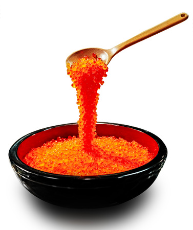 Red caviar dripping from the wooden spoon to the black plate. Protein healthy foodの写真素材