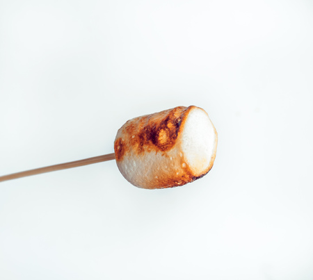 roasted marshmallows on a skewer on white backgroundの写真素材