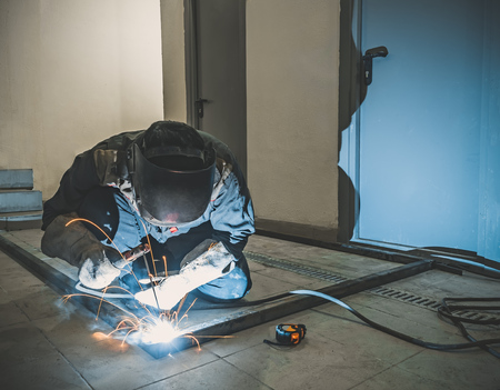 Welder Worker Performs Jump Welding. Worker Welder Performs Arc-Welding Process of Metal Structures....