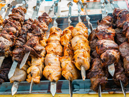 Cooking shashlik on a metal skewer and grilled vegetables. Grilled meat and vegetables. Delicious street food.の写真素材