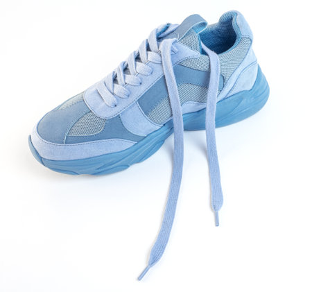 One unlaced light blue sneaker on a white background. Sports shoesの写真素材