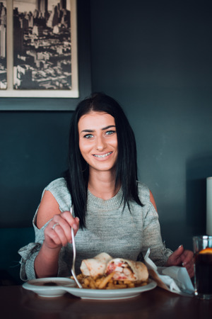 Cheerful woman is about to eat, she smiles to camera man.の写真素材