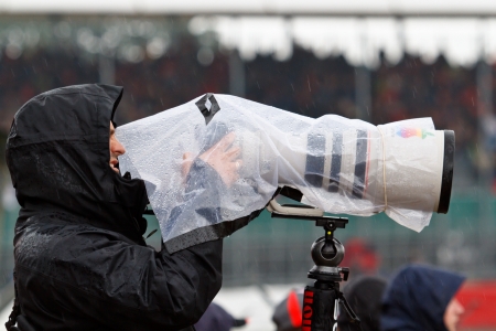 SILVERSTONE, UK - JULY 6: Photographer takes shots in heavy rain during practice session of F1 British GP on July 6, 2012 in Silverstone. Difficult weather conditions are typical for this race.のeditorial素材