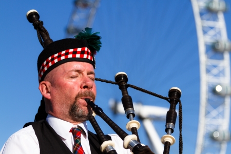 LONDON - NOVEMBER 14: Piper in stylish outfit plays songs on Westminster Bridge with London Eye in background on November 14, 2012 in London.のeditorial素材