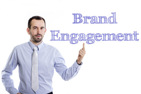 Brand Engagement - Young businessman with small beard pointing up in blue shirt - horizontal imageの写真素材