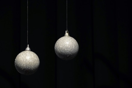 Two hanging silver Christmas balls on dark background with spaceの写真素材