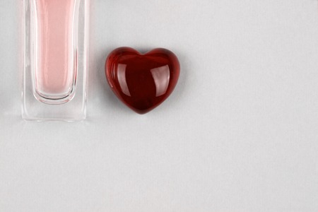 Set of parfume bottle in color of living coral and red heart as a symbol of gift with loveの写真素材