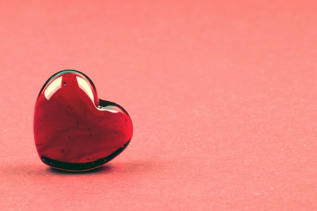 Stylish red heart as a symbol of love and Valentines day on coral backgroundの写真素材