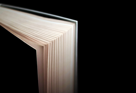Book with hard cover with sheets in bokeh. Isolated on blackの写真素材