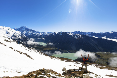 Hiker on top of mountain looking at Mount Cook