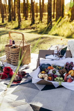 Romantic picnic set up with mixed food platter and wine at sunsetの写真素材