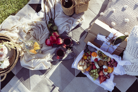 Romantic picnic set up with mixed food platter and wine at sunsetの写真素材
