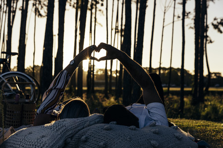 Romantic couple having a picnic at sunset near forestの写真素材