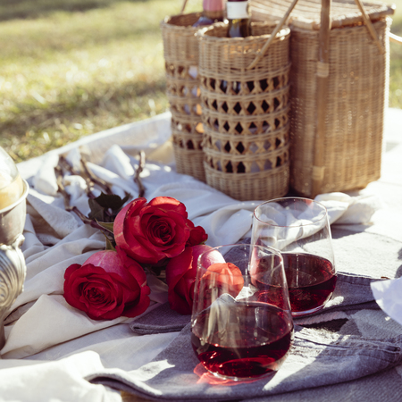 Romantic picnic set up with roses and wine at sunsetの写真素材