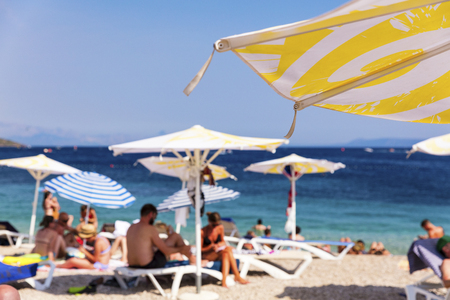 Mediterranean beach with tourists and beach umbrella, focus on umbrellaの写真素材