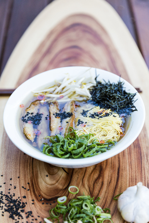 Fake chicken vegan ramen noodle soup on wooden chopping boardの写真素材