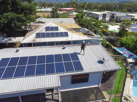 Solar panel technician with drill installing solar panels on roof on a sunny day