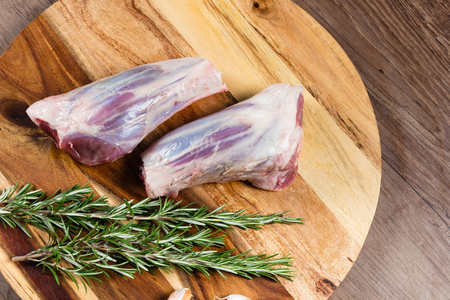 Raw lamb shanks on chopping board with herbsの写真素材