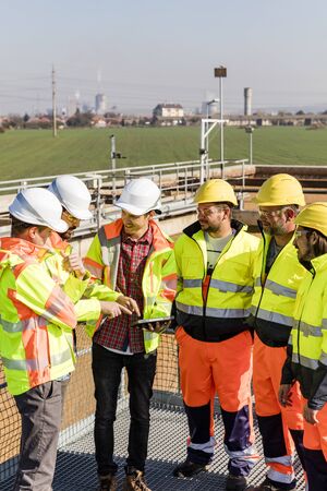 Engineers and workers assesing wastewater plant performance on tablet