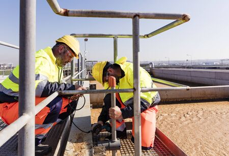 Workers on site of wastewater treatment plant fixing sensorsの写真素材
