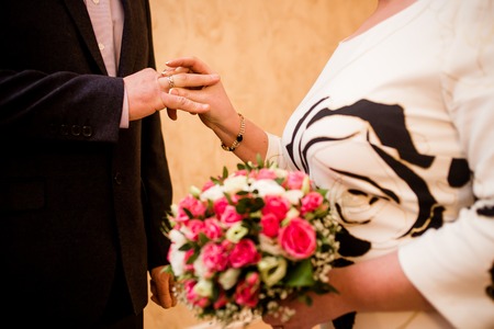 Bride putting a wedding ring on groom's finger. Close up.の写真素材