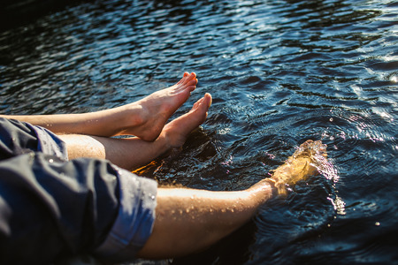 Couple legs in the water splashing with bouquet of  flowers. Summer joy concept.の写真素材